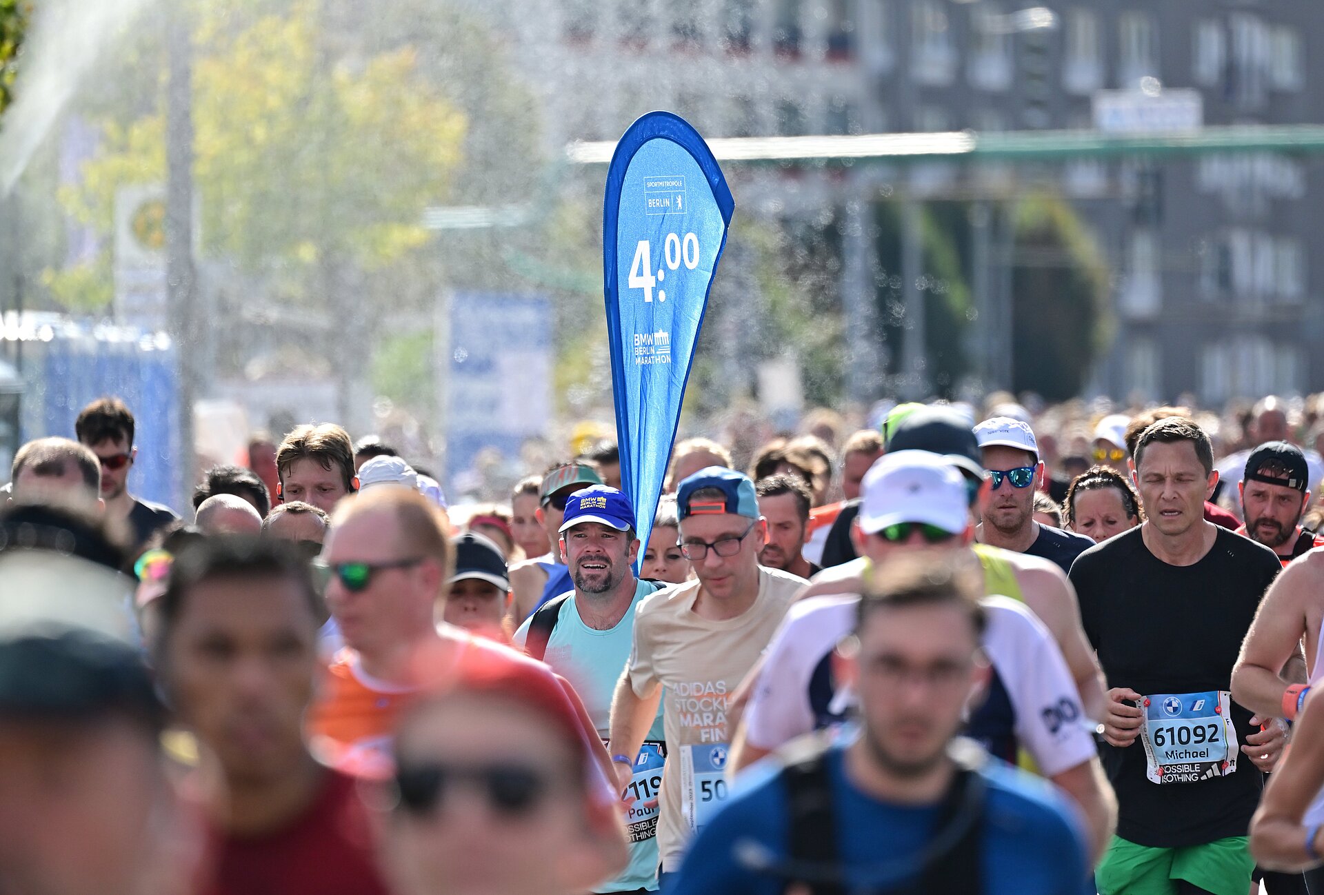 A pacer at the BERLIN-MARATHON. His flag, displaying his finishing time, stands out from the crowd.