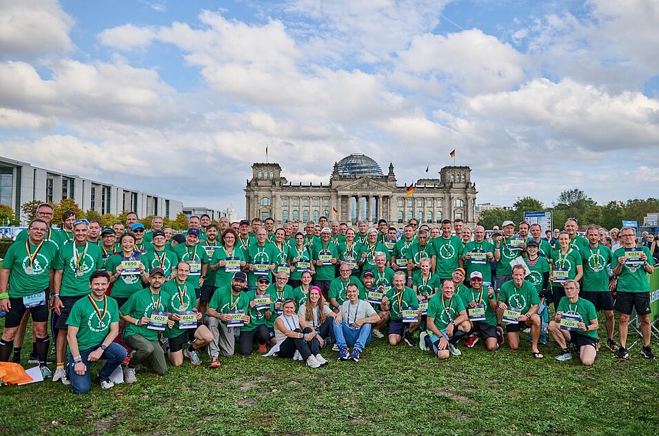 Runners in green Jubilee T-shirts on the Reichstag lawn, with the Reichstag clearly visible in the background.