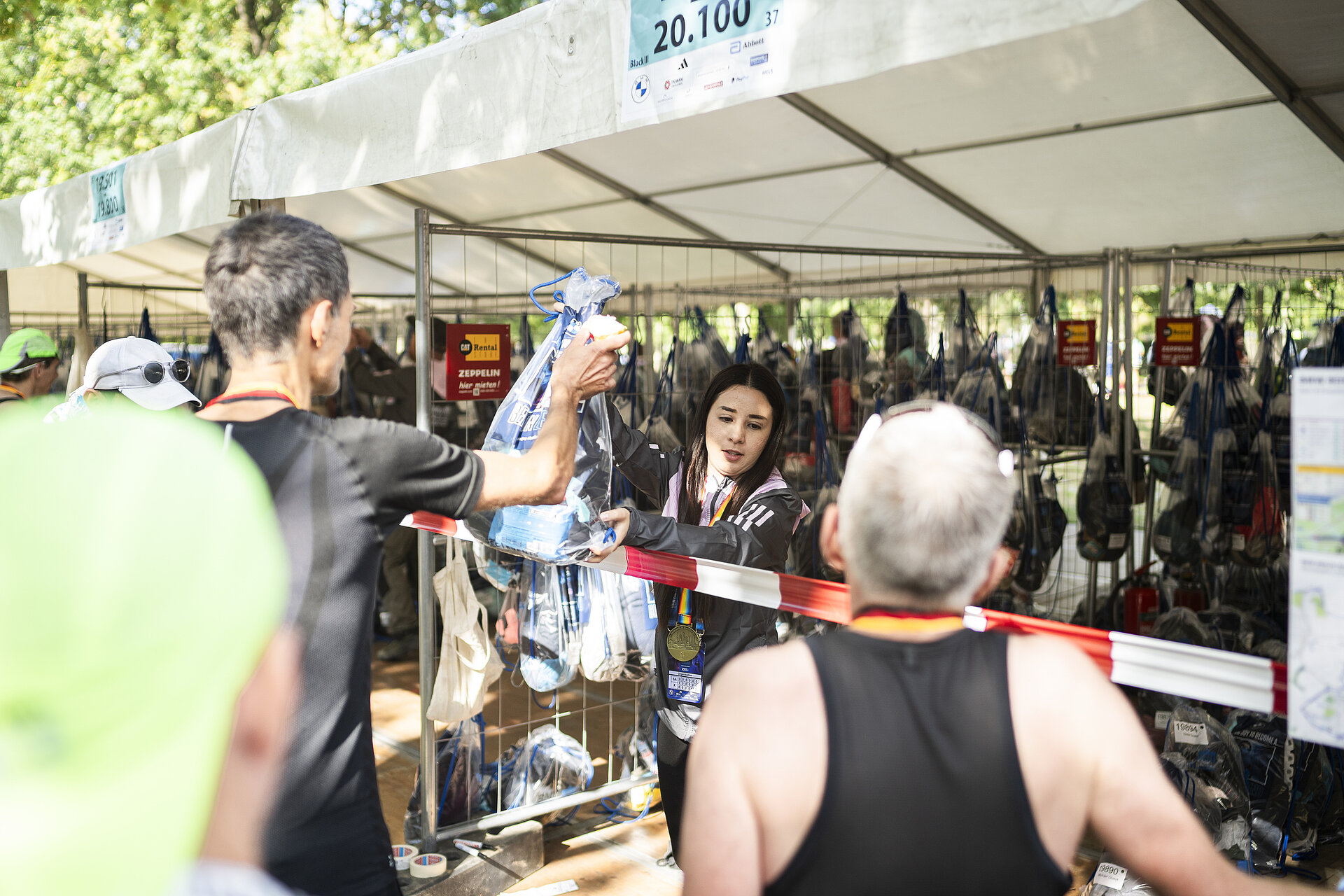 An elongated tent for clothing drop-off, with bib number ranges above each section.