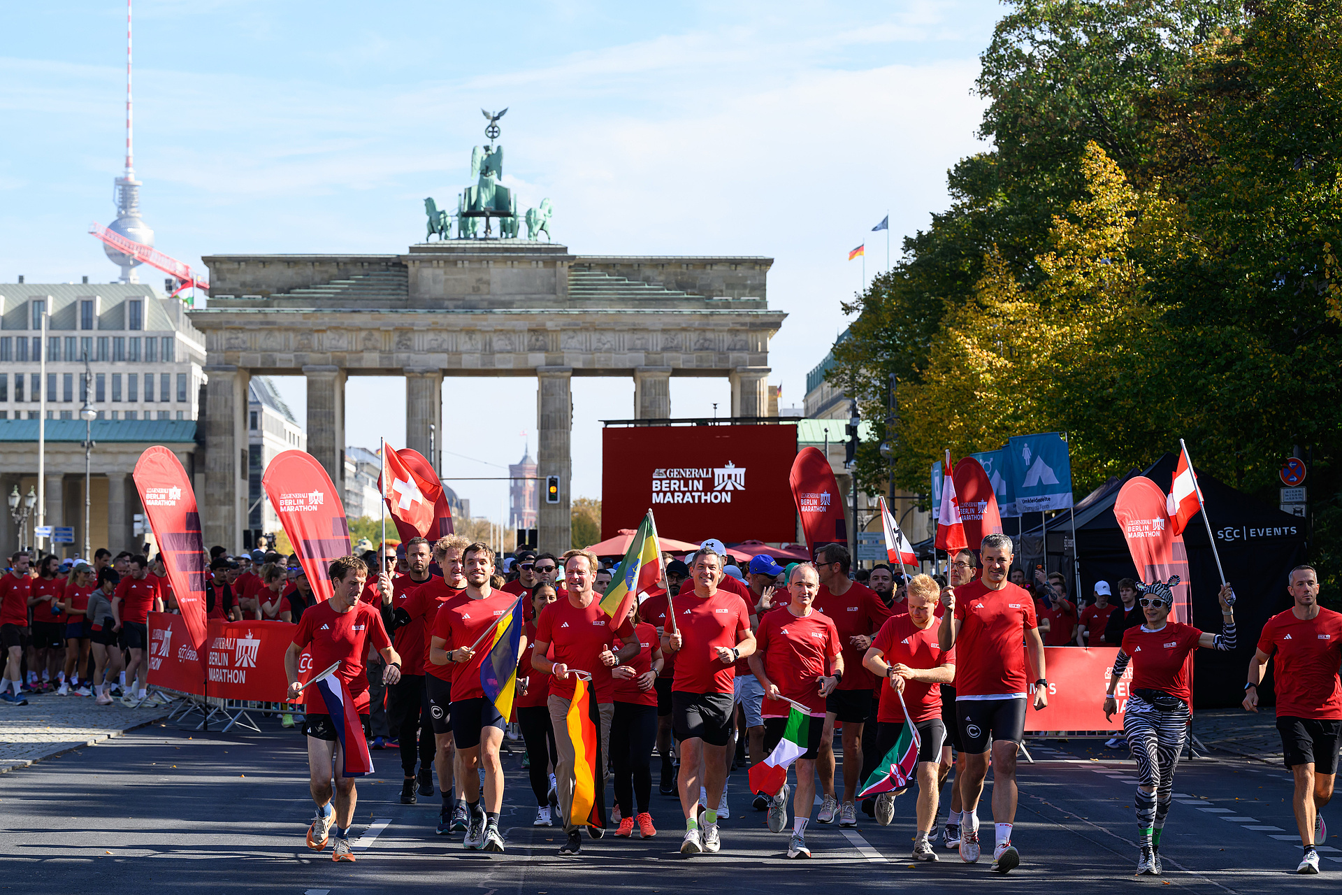 Der Start des Registration Run mit Teilnehmenden, alle in rot gekleidet und mit verschiedenen Fahnen vor dem Brandenburger Tor.