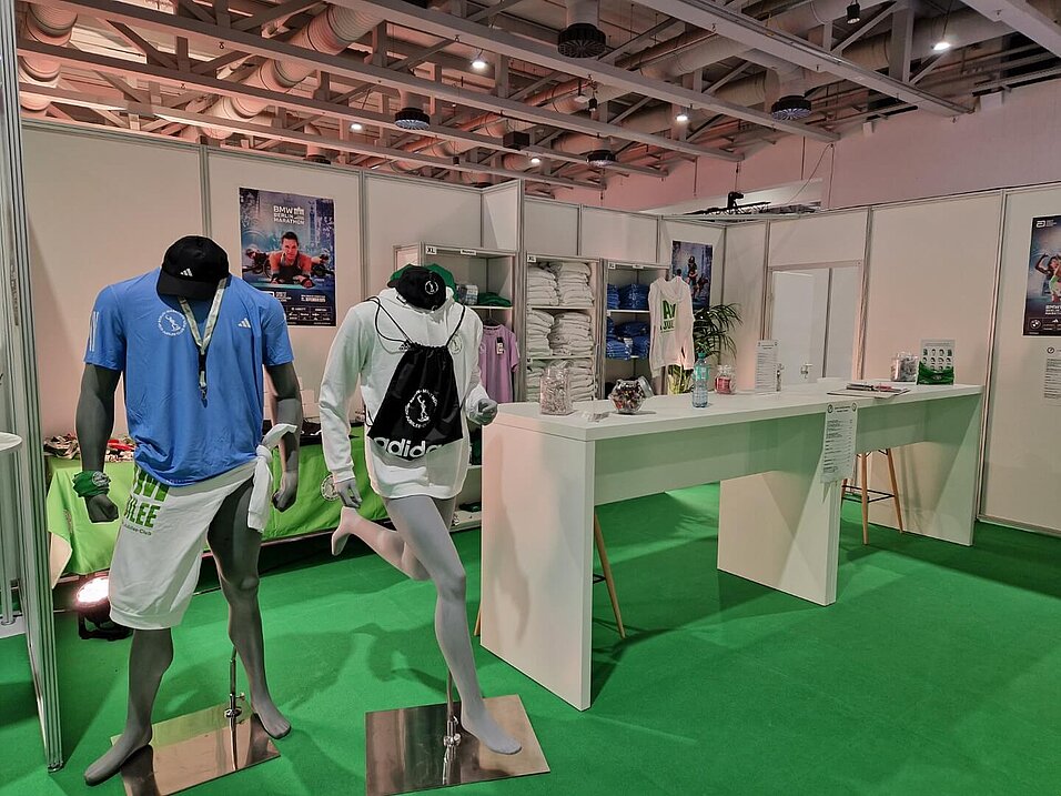 Fläche mit Merchandise, darunter Shirts, Sweater und Turnbeutel, drapiert über zwei KleiderAn area displaying merchandise, including T-shirts, jumpers and gym bags, draped over two mannequins.puppen.