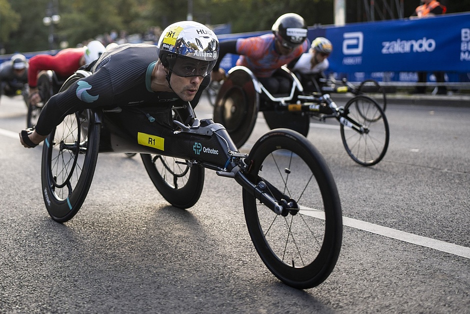 Marcel Hug kurz nach dem Start in seinem Rennrollstuhl. Im Hintergrund weitere Athleth:innen.