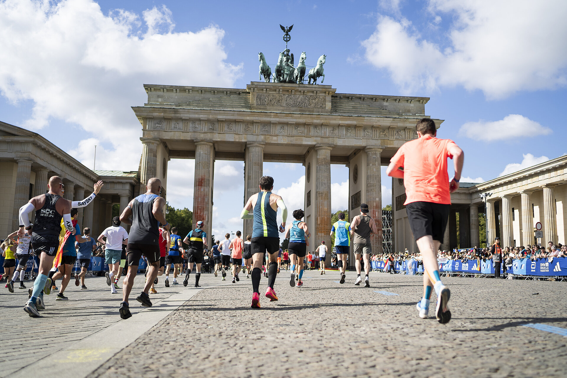 Runners are running toward the Brandenburg Gate.