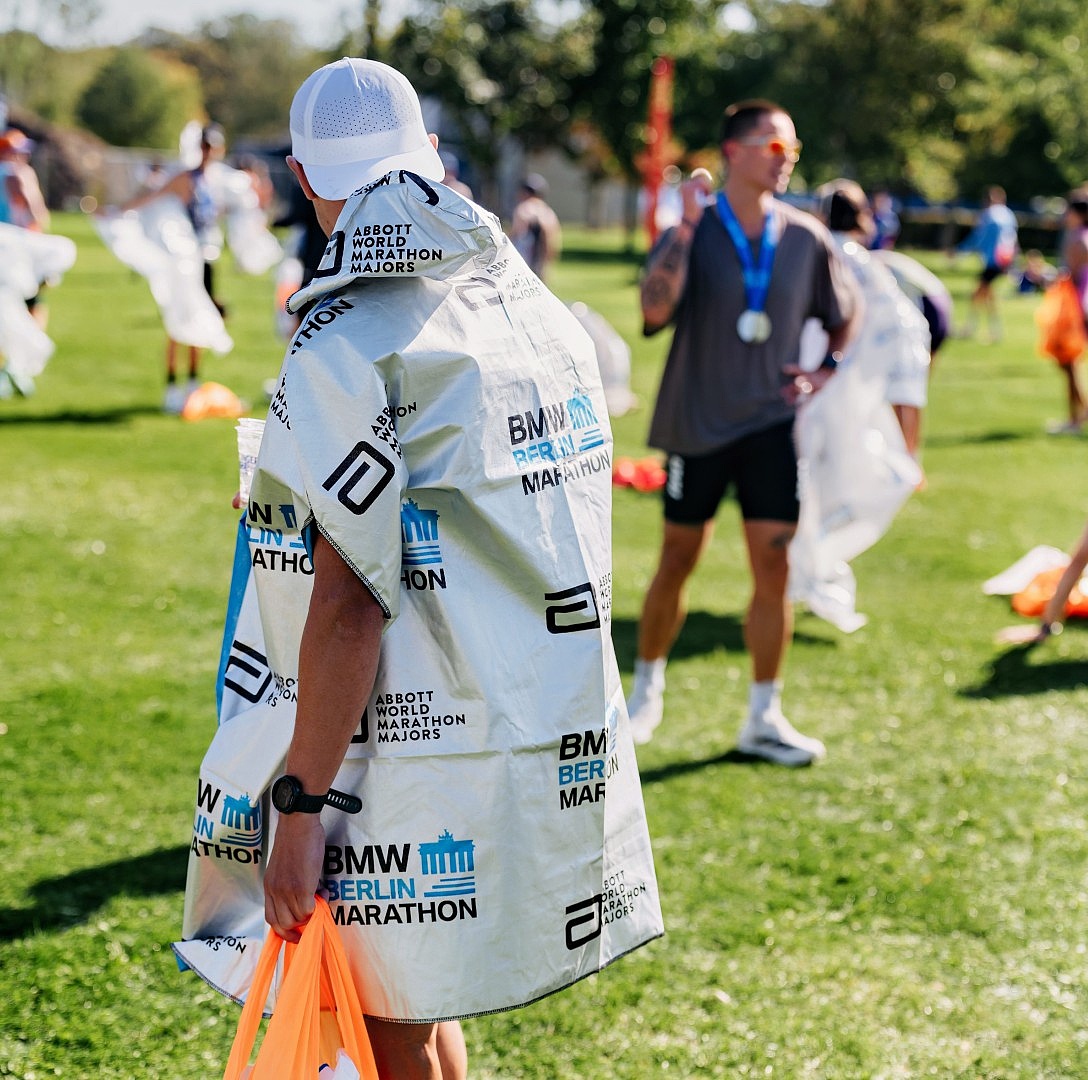 Marathon finishers wear a silver plastic poncho with the BMW BERLIN-MARATHON logo.
