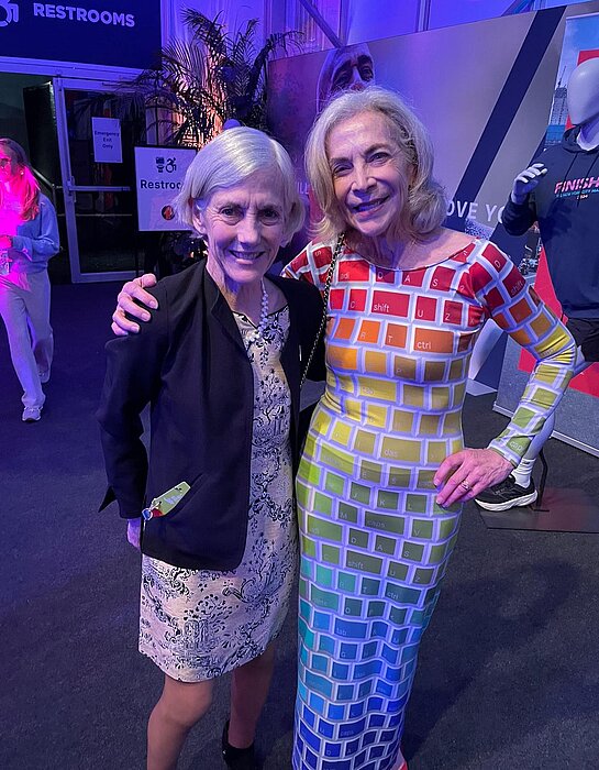 Joan Benoit-Samuelson and Kathrine Switzer pose smiling for the camera.