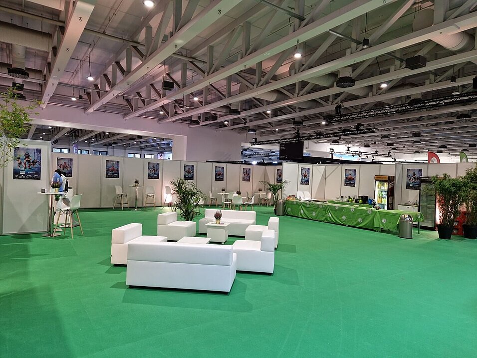 A spacious lounge with a central seating area, tables, chairs, plants and a food counter.