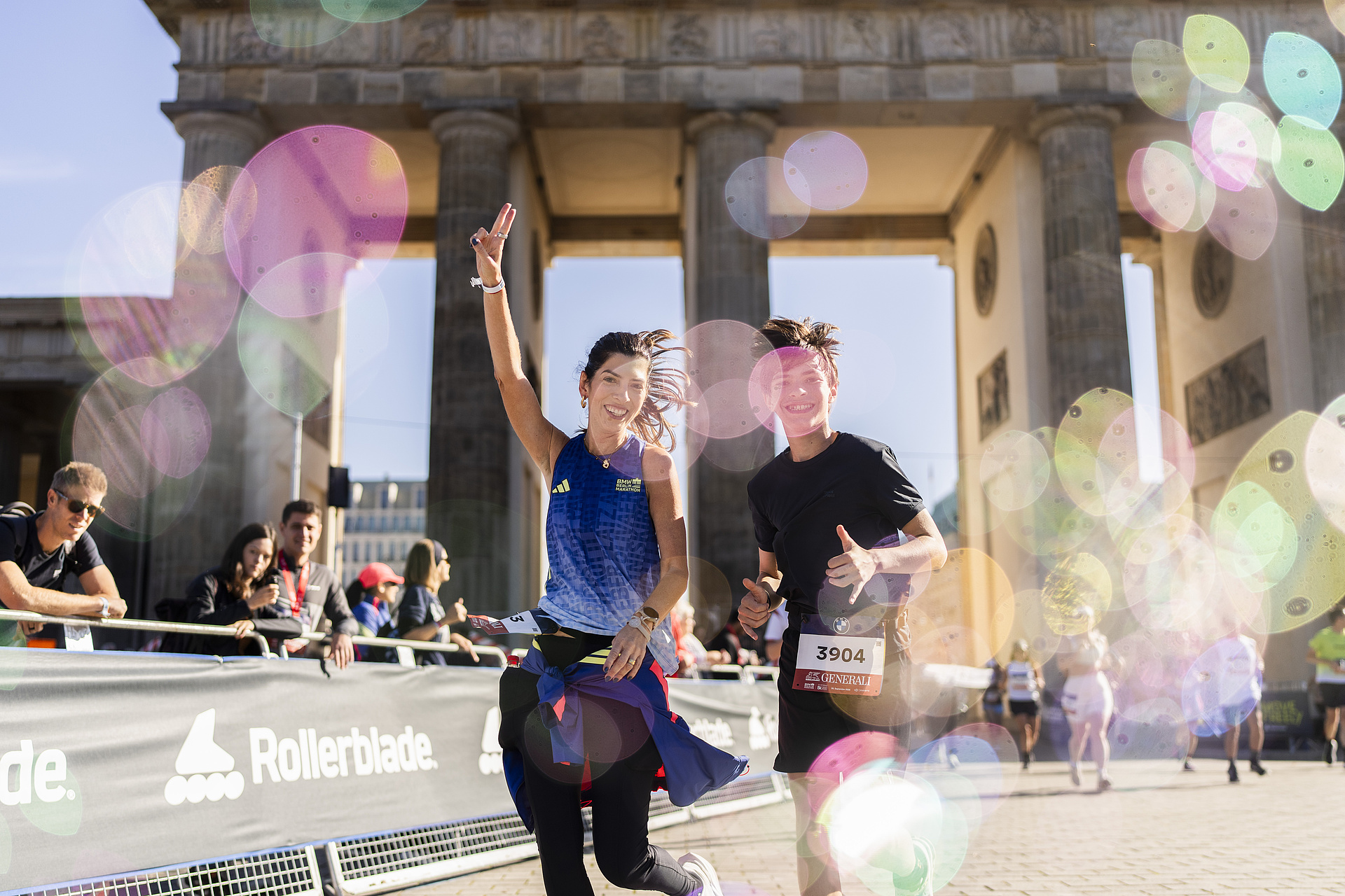 Two runners who have just run through the Brandenburg Gate and are beaming at the camera.