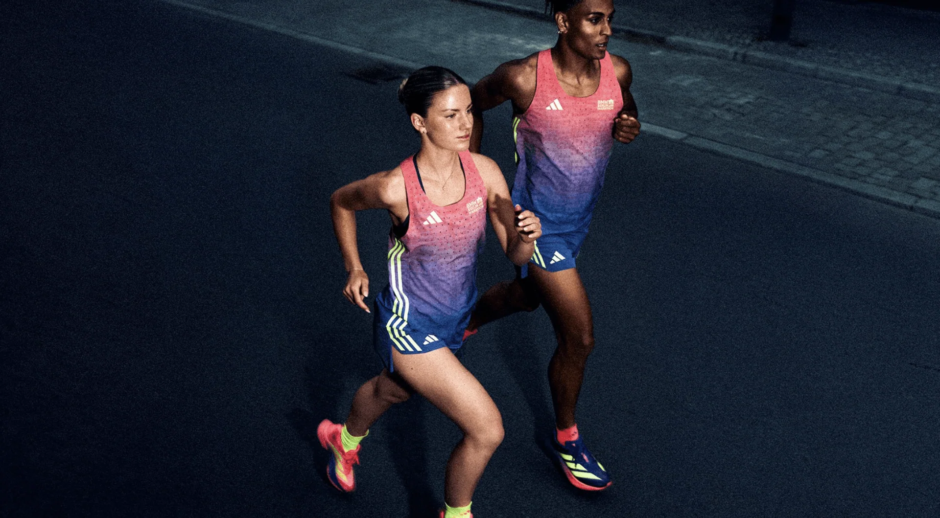 Zwei Läufer:innen in der Marathon-Kollektion 2026 von adidas beim Joggen in der Dämmerung.